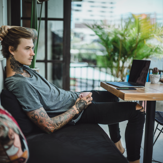 Tattooed man relaxing with laptop