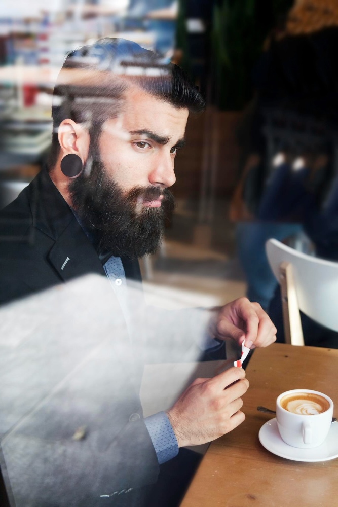Adult man with a beard enjoying coffee outdoors in Oregon, representing clients who feel better after virtual therapy sessions in Oregon