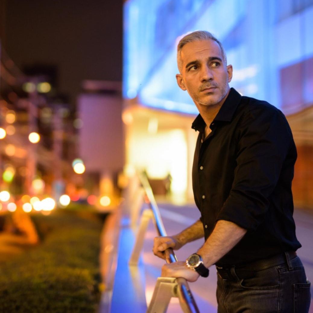 Man standing alone in an urban setting at night looking reflective — representing the anxiety and overthinking treated in anxiety therapy